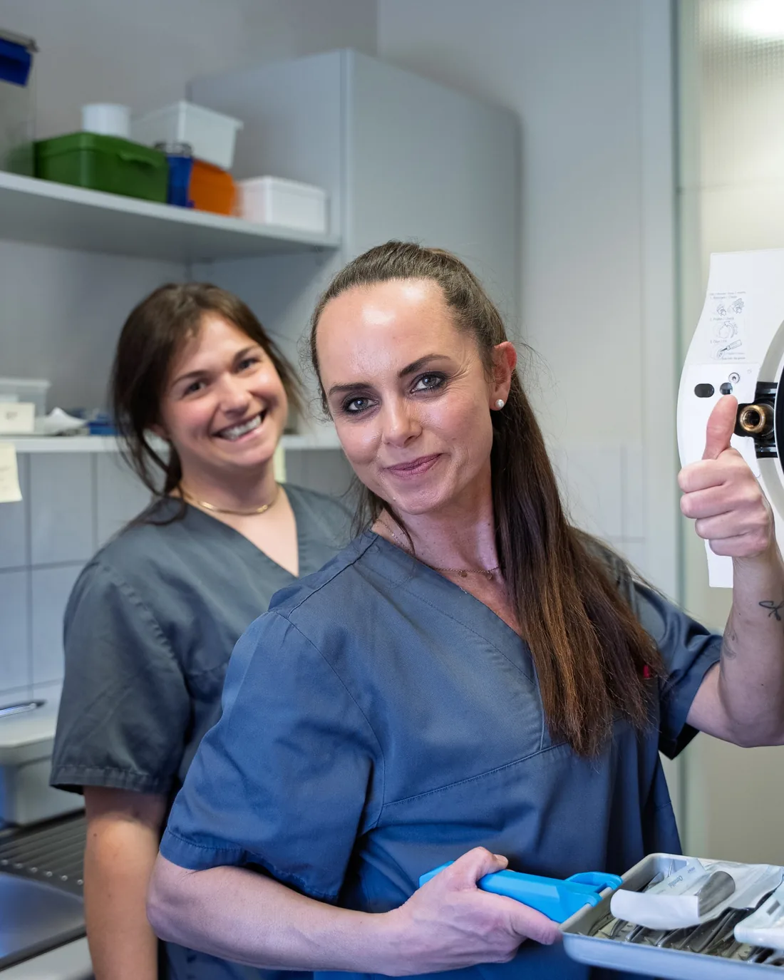 Zwei Kolleginnen der Praxis Dr. Hunecke in der Behandlungsassistenz, eine zeigt den Daumen nach oben